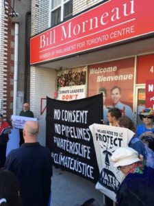 in front of MP Bill Morneau's office in Toronto Centre, with sign 'no consent, no pipelines! Water is life. #climatejustice.