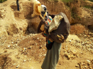 woman carrying rocks from coltan mine