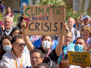 People at climate rally. Woman holds up sign that reads: Climate Crisis!