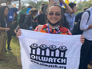 Ivonne Yanez walking with other marchers and carrying a sign that reads OILWATCH